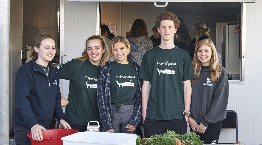 High school students participate in a soup kitchen as part of their volunteering with children in South Africa through Projects Abroad High school students prepare meals during volunteer work in South Africa for teenagers